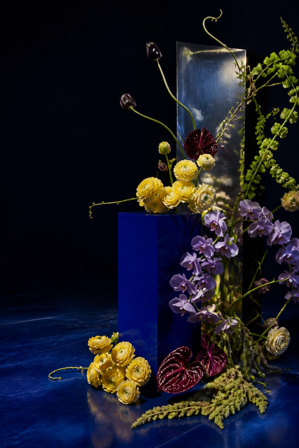 Studiu vizual generat: instalație florală sculpturală cu panou cobalt într-un decor albastru închis.
